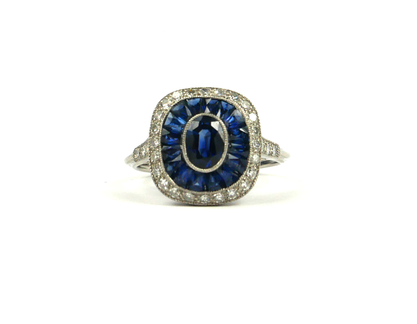 A PLATINUM ART DECO STYLE, SAPPHIRE AND DIAMOND RING. The Centre oval shaped sapphire surrounded