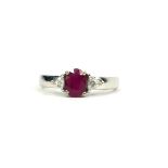 AN 18CT WHITE GOLD OVAL RUBY RING flanked by trillion cut diamonds. (Ruby 1.00ct, Diamonds 0.13ct
