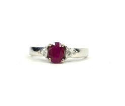 AN 18CT WHITE GOLD OVAL RUBY RING flanked by trillion cut diamonds. (Ruby 1.00ct, Diamonds 0.13ct