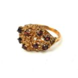 A VINTAGE 9CT GOLD AND GARNET CLUSTER RING Having an arrangement of round cut garnets in a