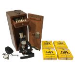 A 20TH CENTURY BRITISH MICROSCOPE IN A WOODEN CARRY CASE Along with various microslides, Aston &