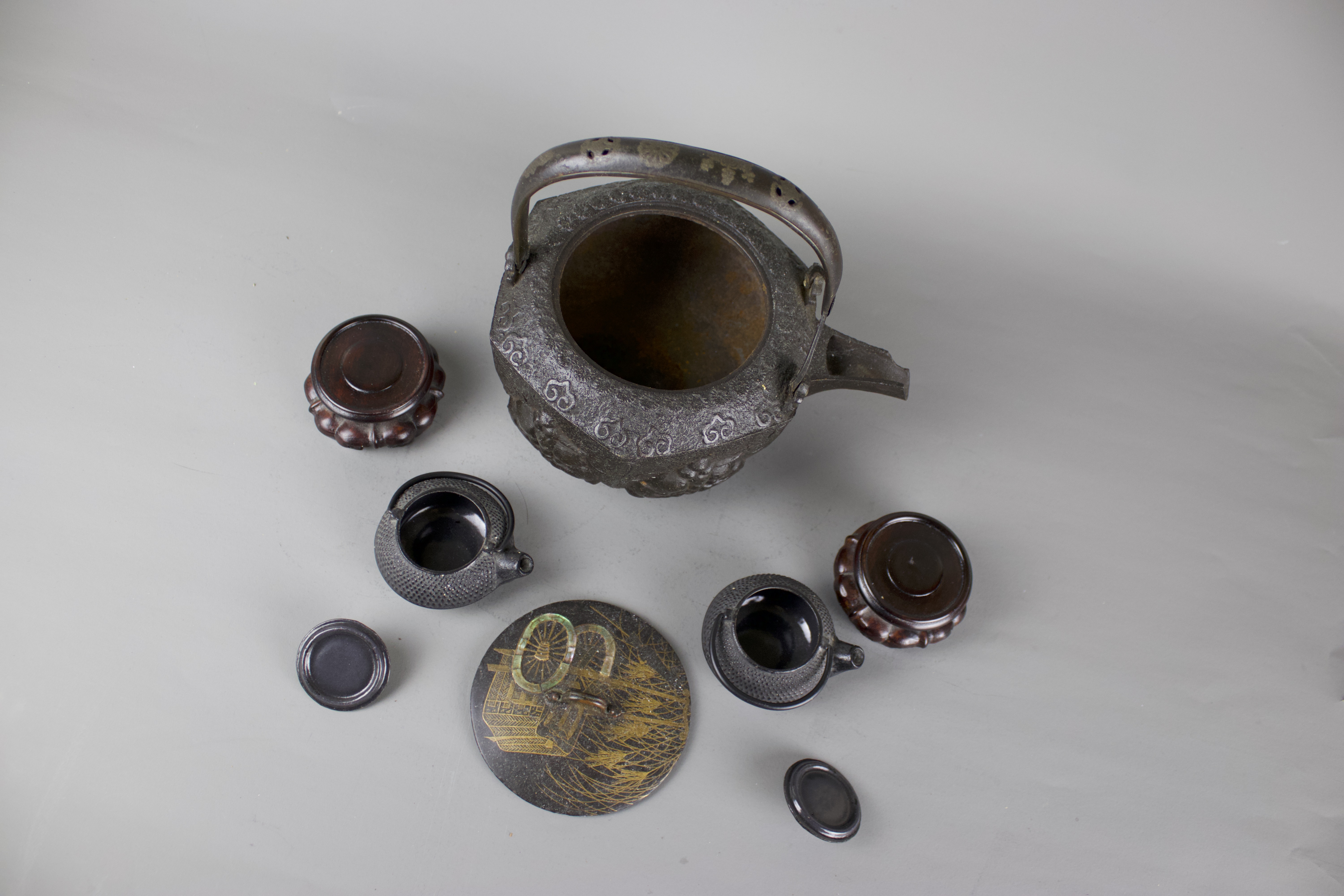 A Japanese cast iron tebsubin, 19th C and a pair of cast iron mini teapots on wooden stands, 20th C. - Image 5 of 6