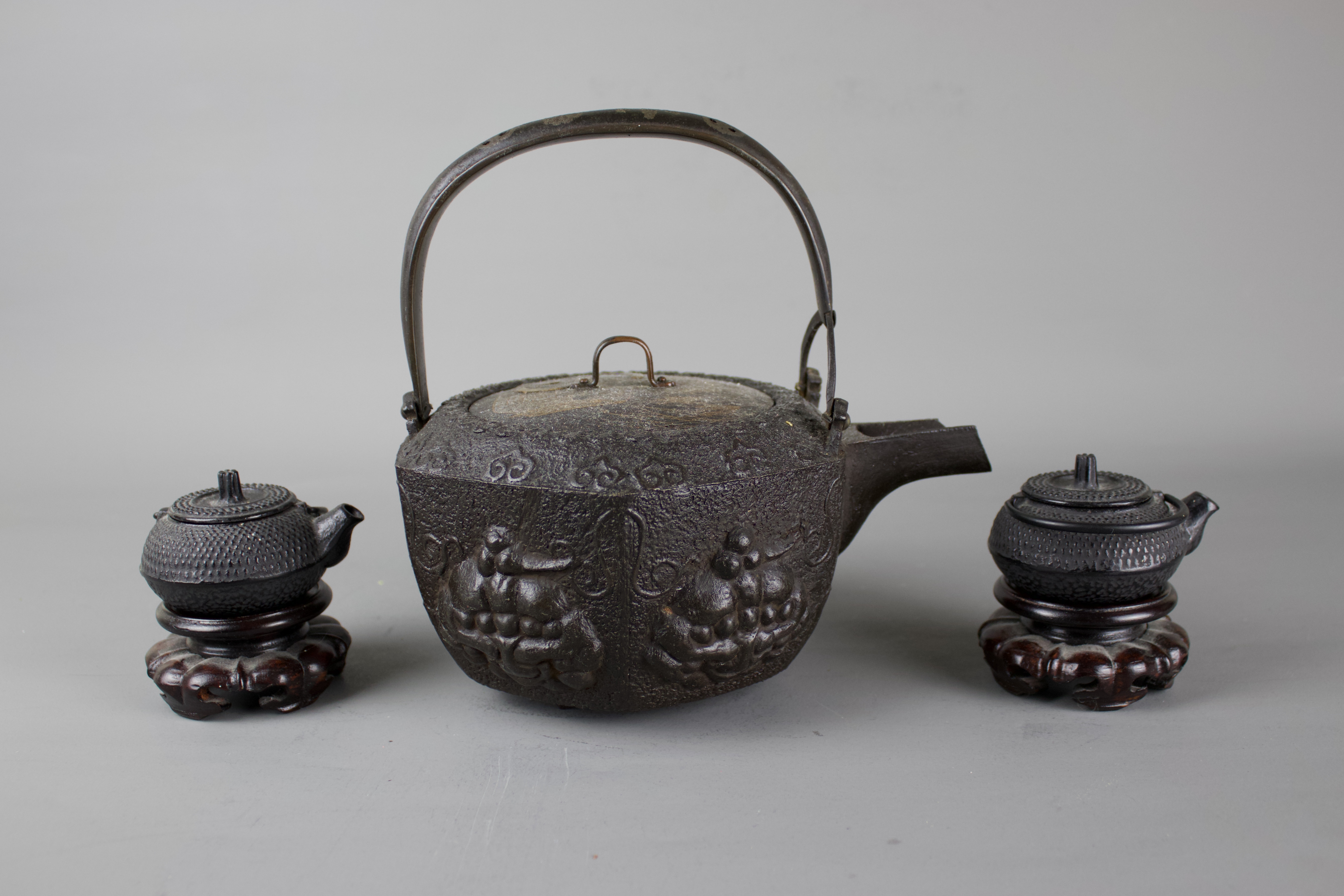 A Japanese cast iron tebsubin, 19th C and a pair of cast iron mini teapots on wooden stands, 20th C. - Image 4 of 6