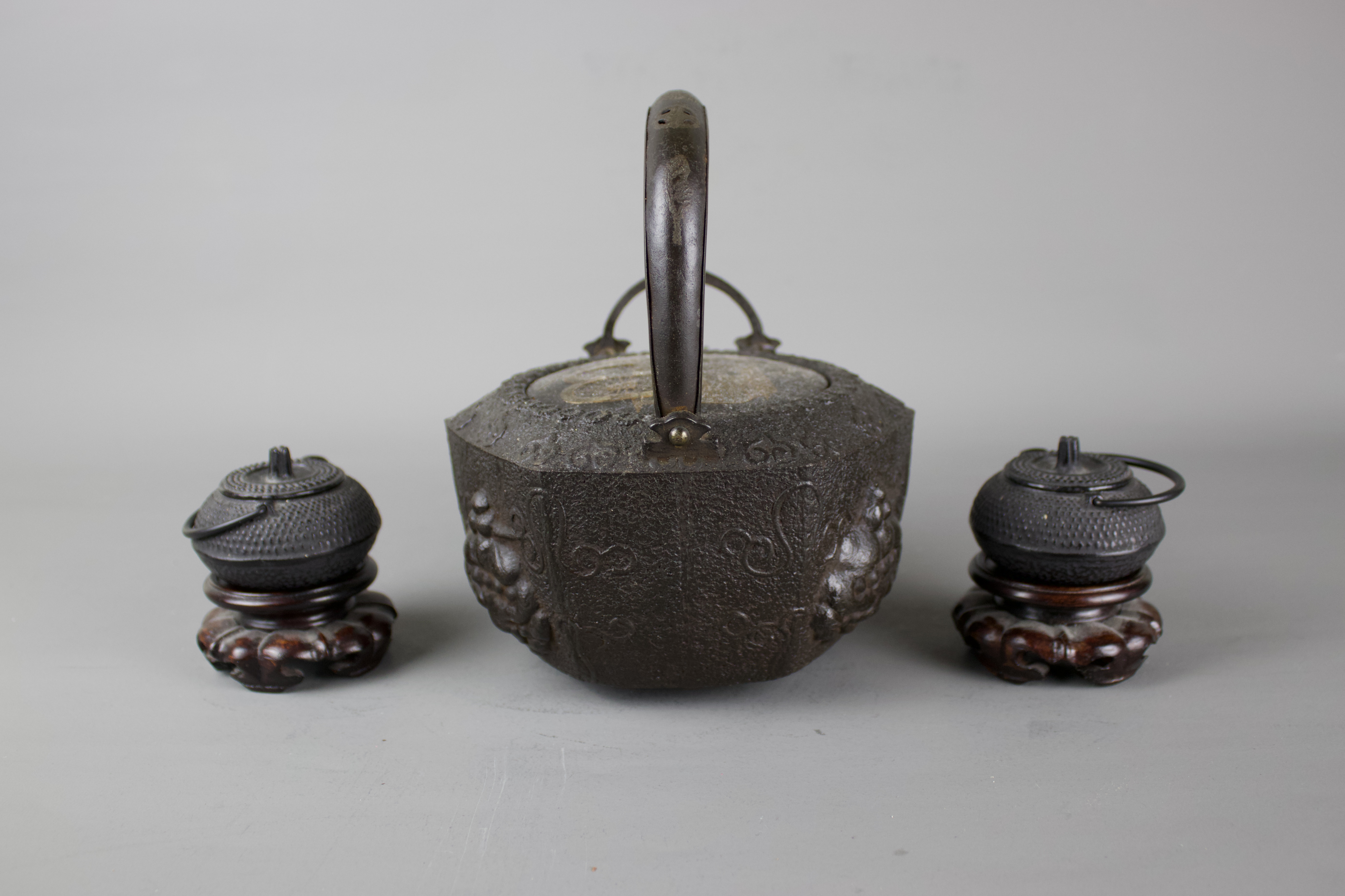 A Japanese cast iron tebsubin, 19th C and a pair of cast iron mini teapots on wooden stands, 20th C. - Image 3 of 6