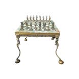 PIERO BENZONI, AN EGYPTIAN REVIVAL PHARAOHS GILT AND SILVERED CHESS SET AND TABLE Each piece