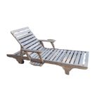 A TEAK GARDEN LOUNGER With slatted rails and incorporated extendable side/drinks table, complete