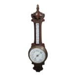 AN EDWARDIAN OAK AND BRASS BAROMETER Having a banjo form carved oak case, set with mercurial