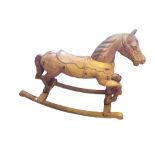 A 20TH CENTURY CARVED PINE ROCKING HORSE With a long carved saddle, raised on pine rockers. (