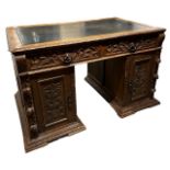 A 19TH CENTURY CARVED OAK PEDESTAL DESK The tooled leather top above two drawers and panelled doors,