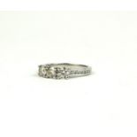 AN 18CT WHITE GOLD THREE STONE DIAMOND RING WITH DIAMOND SHOULDERS. (Approx Solitaire diamond 0.