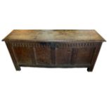 A LARGE 18TH CENTURY CARVED OAK FOUR PANNED COFFER With rising hinge lid, raised on square section