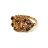 A VINTAGE 9CT GOLD AND GARNET CLUSTER RING Having an arrangement of round cut garnets in a