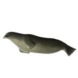 A 20TH CENTURY INUIT CARVING OF A SEAL LAYING ON ITS SIDE, SIGNED INDISTINCTLY TO
