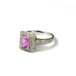 AN 18CT WHITE GOLD, EMERALD CUT PINK SAPPHIRE AND PAVÉ SET ROUND CUT DIAMOND CLUSTER RING. (sapphire