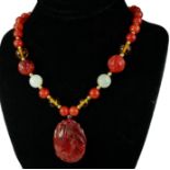 A CHINESE CARVED CARNELIAN PENDANT AND BEAD NECKLACE Pendant having a pierced and stylised carved