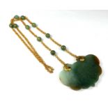 A LARGE 14CT GOLD AND CARVED JADE PENDANT Suspended by a jade and gold link necklace. (gross