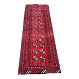 AN AFGHAN BOKHARA WOOLLEN CARPET AND RUNNER The central field decorated with geometric motifs in