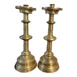 A PAIR OF LARGE CONTINENTAL BRASS ECCLESIASTICAL CANDLESTICKS The pierced drip trays above turned