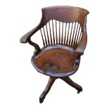 AN EARLY 20TH CENTURY OAK CAPTAIN'S CHAIR Spindle back with scrolled arms, saddle seat and swivel