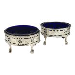 A PAIR OF GEORGIAN SILVER AND BLUE GLASS OVAL SALTS With pierced and engraved decoration, on ball