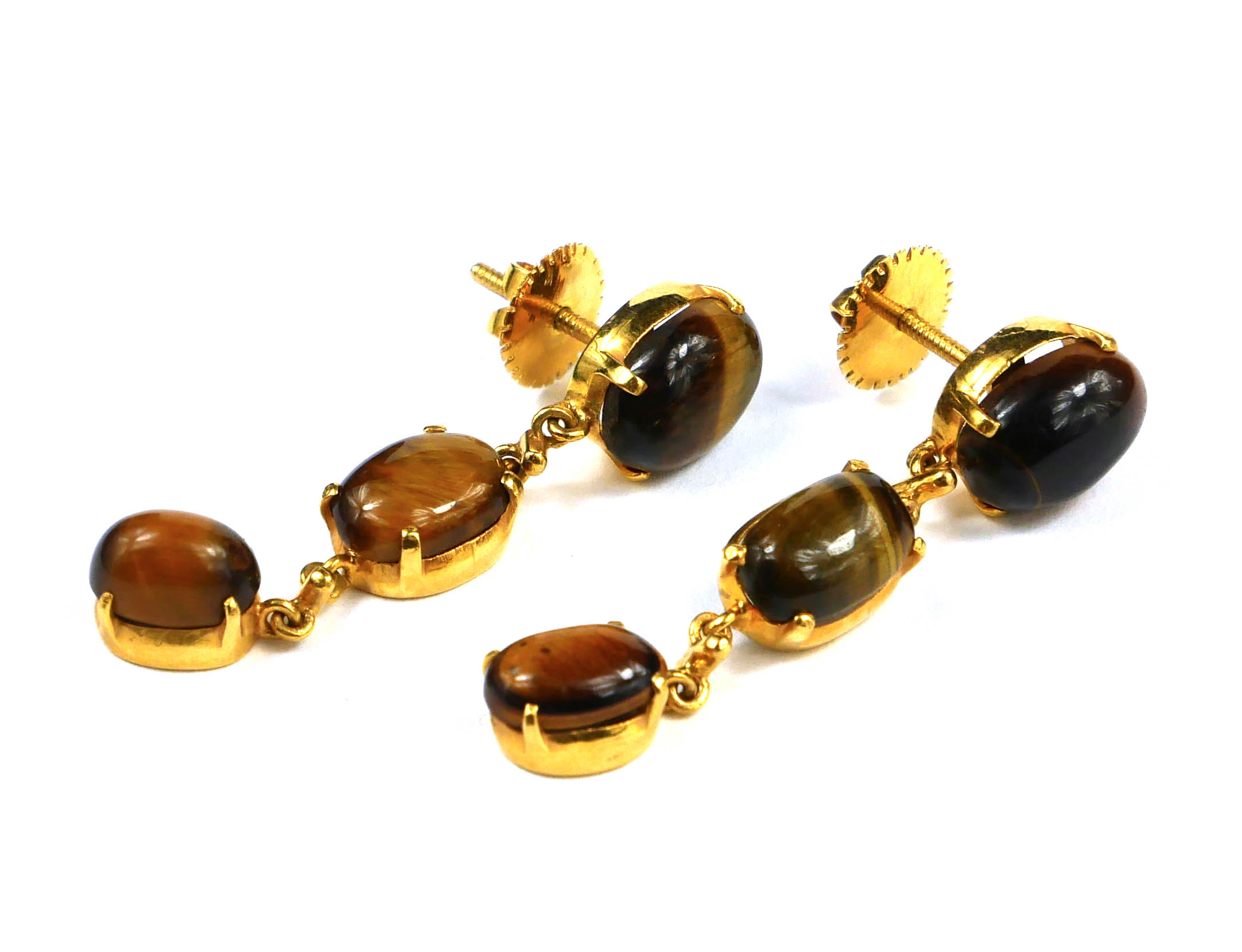 A PAIR OF YELLOW METAL AND TIGER'S EYE DROP EARRINGS Set with three graduated oval cut stones on