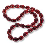 A STRING NECKLACE OF THIRTY-TWO LARGE OVAL AMBER BEADS. (length 41cm) Condition good