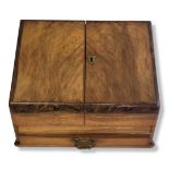 AN EDWARDIAN WALNUT STATIONARY CABINET Having a sloped front with twin doors, opening to reveal a