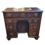 A GEORGIAN AND LATER MAHOGANY KNEEHOLE DESK Having an an arrangement drawers fitted with brass