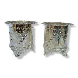 A PAIR OF SILVER PLATED WINE BOTTLE HOLDERS Pierced design, embossed to rims, on tripods. (h 13cm)