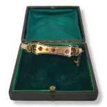 A VICTORIAN 9CT GOLD, GARNET AND DIAMOND BANGLE Having three round cut garnets interspersed with
