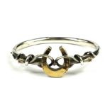 A VICTORIAN WHITE METAL HORSESHOE BANGLE Having a pierced horseshoe with entwined serpents, engraved