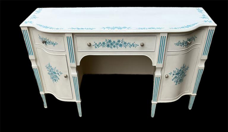 A MID 20TH CENTURY CREAM PAINTED AND BLUE FLORAL DECORATED KNEEHOLE DRESSING TABLE With three