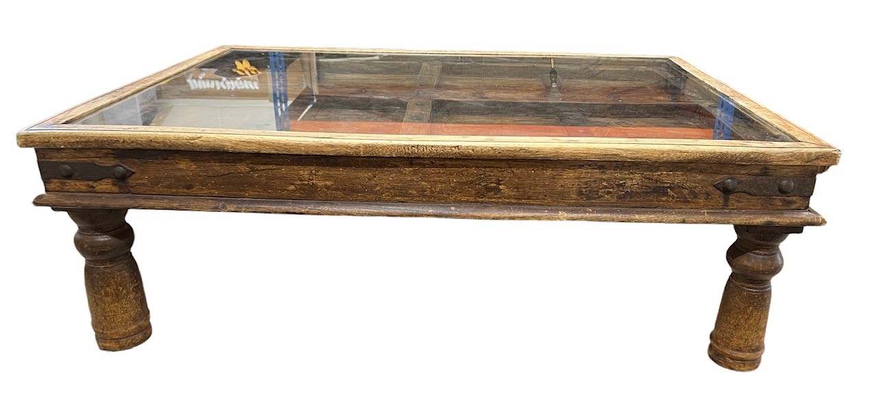 A 19TH CENTURY INDIAN SHEESHAM WOOD COURTYARD DOOR CONVERTED TO COFFEE TABLE WITH GLASS TOP Raised