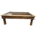 A 19TH CENTURY INDIAN SHEESHAM WOOD COURTYARD DOOR CONVERTED TO COFFEE TABLE WITH GLASS TOP Raised