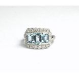 AN 18CT WHITE GOLD AND THREE STONE EMERALD CUT AQUAMARINE AND ROUND CUT DIAMOND CLUSTER DRESS