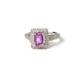 AN 18CT WHITE GOLD, EMERALD CUT PINK SAPPHIRE AND PAVÉ SET ROUND CUT DIAMOND CLUSTER RING. (sapphire