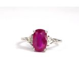 AN 18CT WHITE GOLD THREE STONE RING set with an oval ruby and trilliant cut diamonds. (Ruby 3.