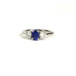 A PLATINUM THREE STONE RING set with oval sapphire and round brilliant cut diamonds. (Sapphire 0.