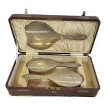 A BOXED HALLMARKED SILVER THREE PIECE DRESSING TABLE SET Chester, 1924, embossed with stylised