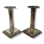 A PAIR OF EARLY 20TH CENTURY SILVER CANDLESTICKS Having embossed floral design and square form base.