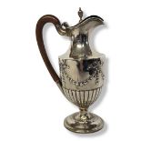 AN EARLY 20TH CENTURY SILVER CLARET JUG Classical form with carved wooden handle and embossed