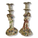 A PAIR OF EARLY 20TH GERMAN PORCELAIN FIGURAL CANDLESTICKS Classical form winged cherub with applied