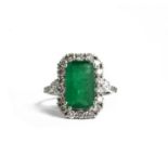AN 18CT WHITE GOLD EMERALD AND DIAMOND CLUSTER RING. (Emerald 3.72ct, Diamonds 1.17ct)