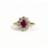A 9CT YELLOW AND WHITE GOLD OVAL RUBY AND DIAMOND CLUSTER RING . (Ruby 0.80ct approx. Diamonds 0.