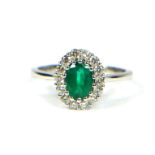 AN 18CT WHITE GOLD, OVAL EMERALD AND DIAMOND CLUSTER RING. (Emerald 0.70ct. Diamonds 0.40ct)