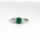 AN 18CT WHITE GOLD EMERALD AND DIAMOND THREE STONE RING. (Emerald 0.82ct, Diamonds 0.60ct)