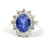 AN 18CT WHITE GOLD, OVAL SAPPHIRE AND ROUND BRILLIANT CUT DIAMOND CLUSTER RING, flanked with diamond