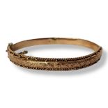 AN EARLY 20TH CENTURY 9CT ROSE GOLD BANGLE Having a rope design to outer edge and engraved