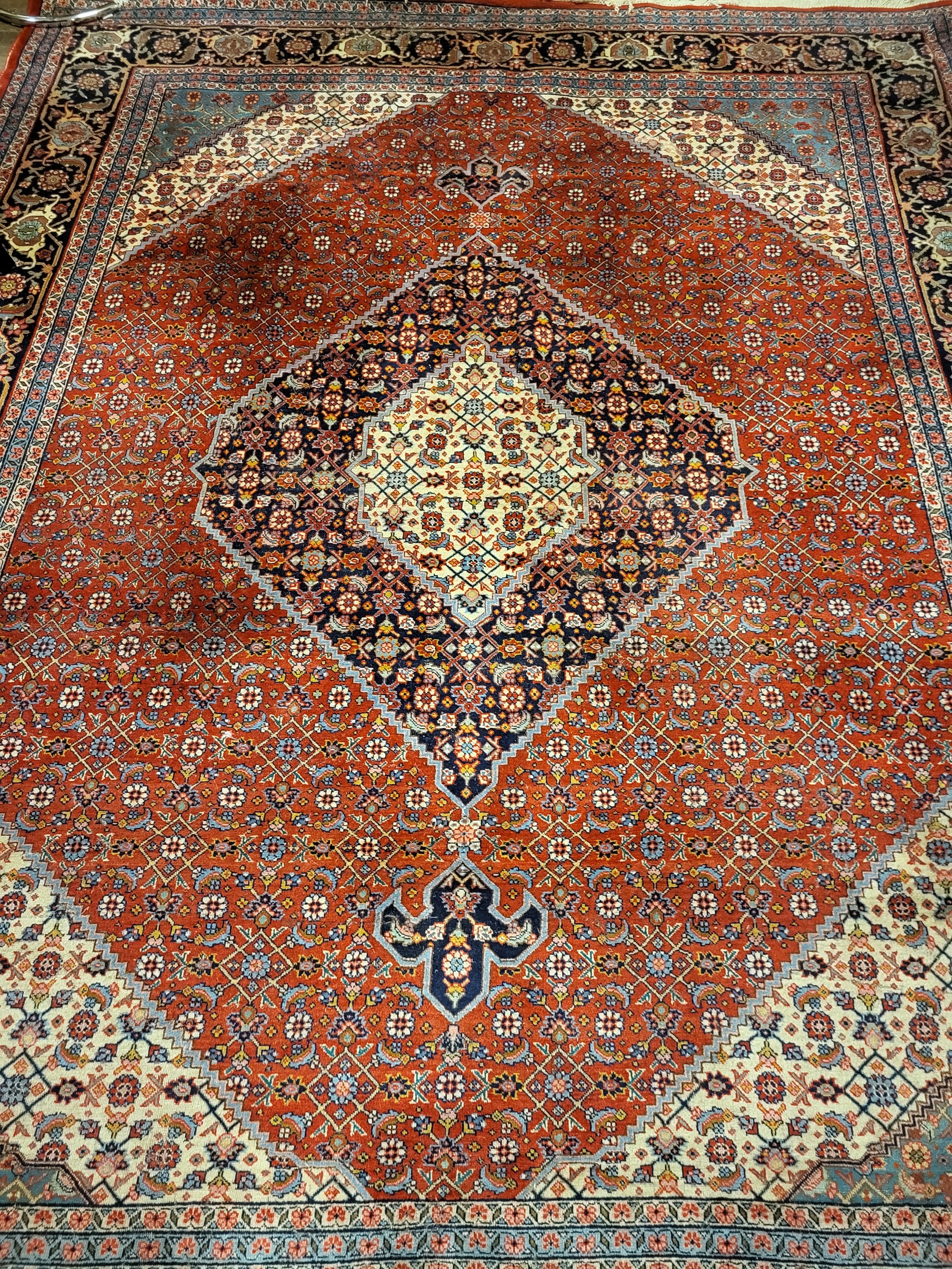 A LARGE INDIAN WOOLLEN RUG OF MIDDLE EASTERN DESIGN With central floral fields contained in seven