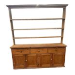 A LARGE PINE FARMHOUSE DRESSER With open shelves above an arrangement of drawers and cupboards. (w